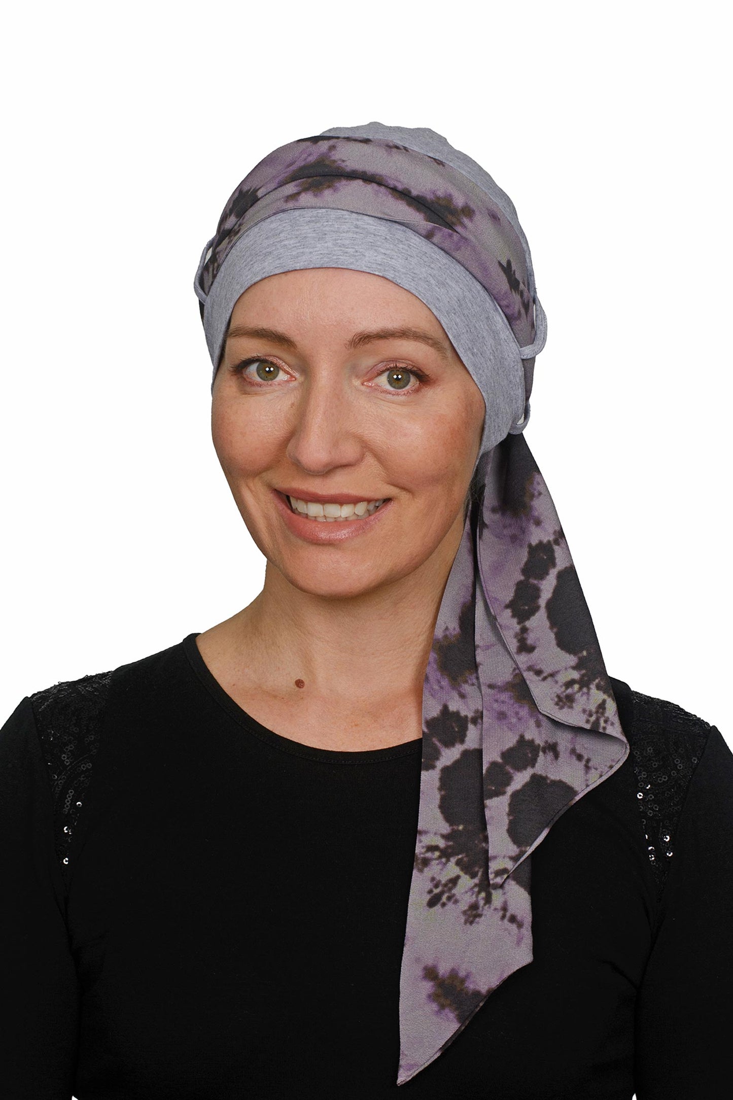 Woman wearing a purple patterned headscarf for cancer patients on a white background