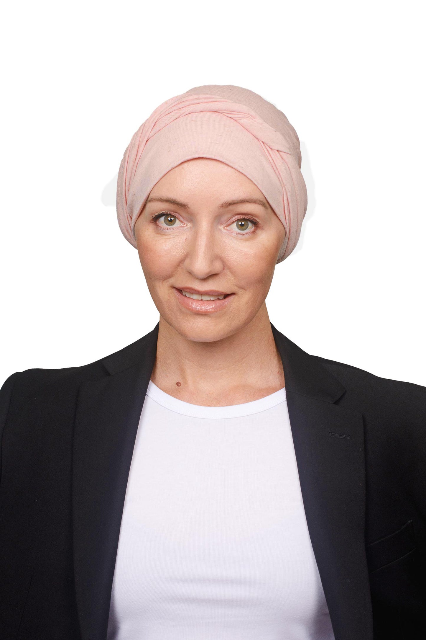 A woman wearing a light pink fabric head covering or turban-style cap, paired with a white top and black blazer, photographed against a plain white background.