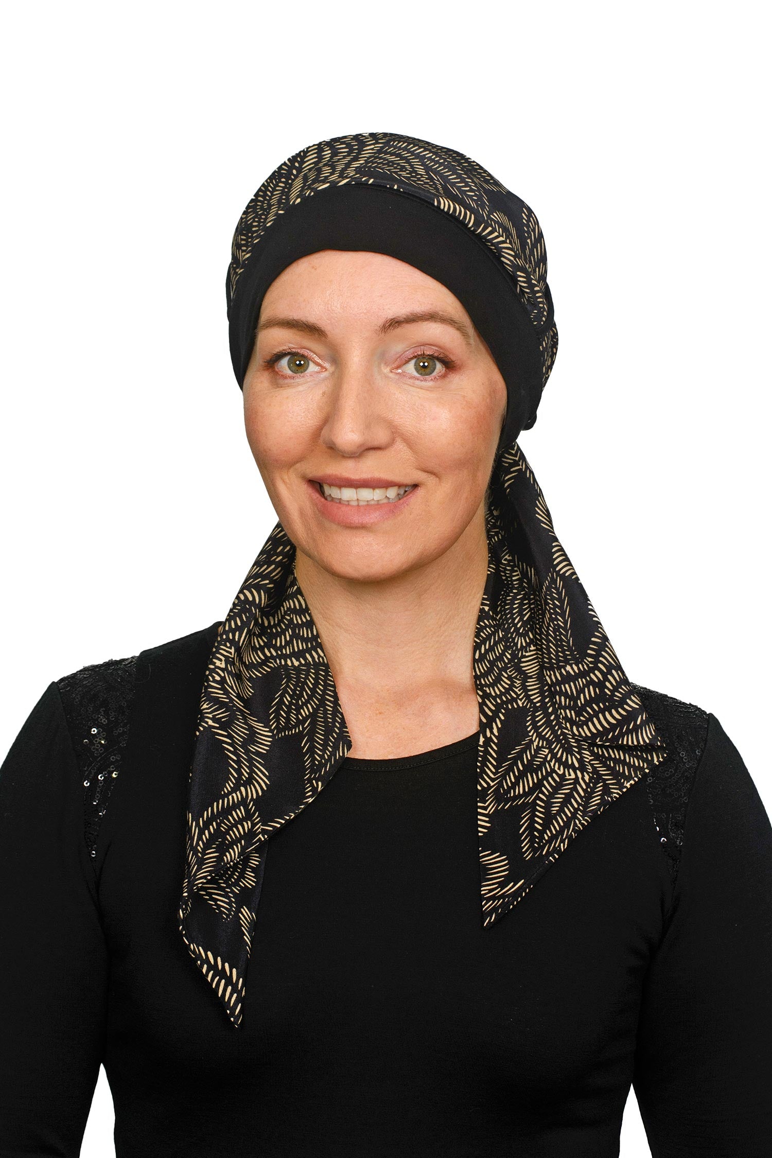 Women wearing a headcovering for cancer that is a scarf and cap seperate in black and a pretty paisley print in sand.