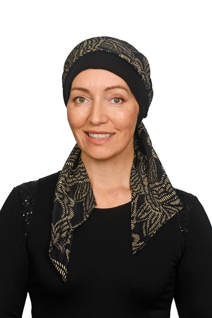 Women wearing a headcovering for cancer that is a scarf and cap seperate in black and a pretty paisley print in sand.