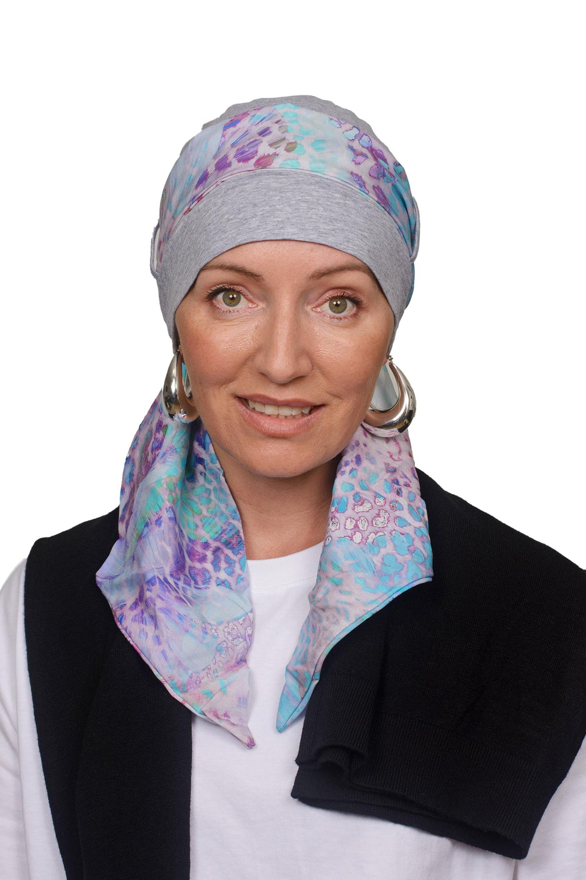 Women wearing a silver marle cap with a light coloured animal print in soft colours scarf through the hat as a headcovering for hair loss