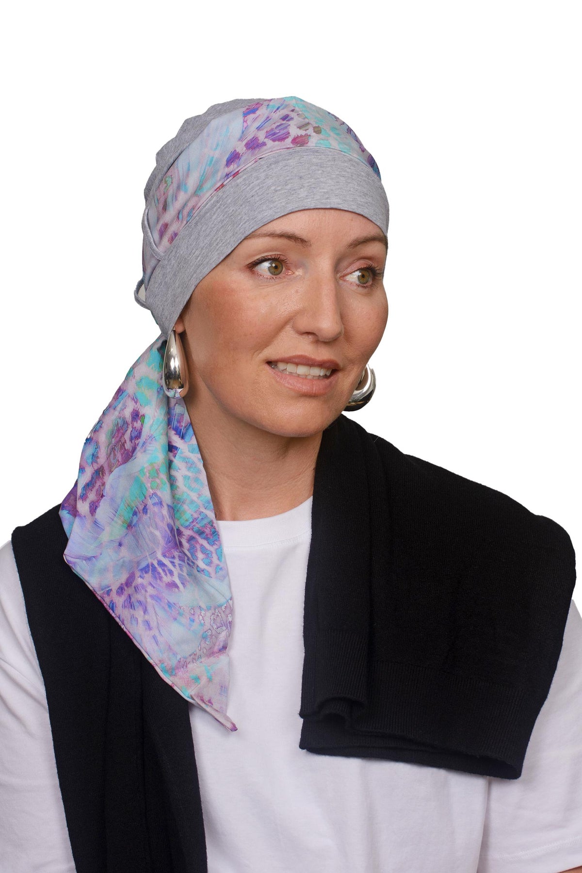 Women wearing a silver marle cap with a light coloured animal print in soft colours scarf through the hat as a headcovering for hair loss