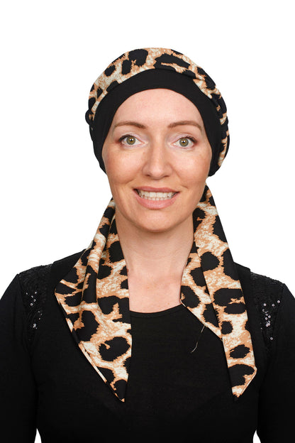 Animal Cancer Cap with a scarf threaded throgh it in black worn as a headcovering.