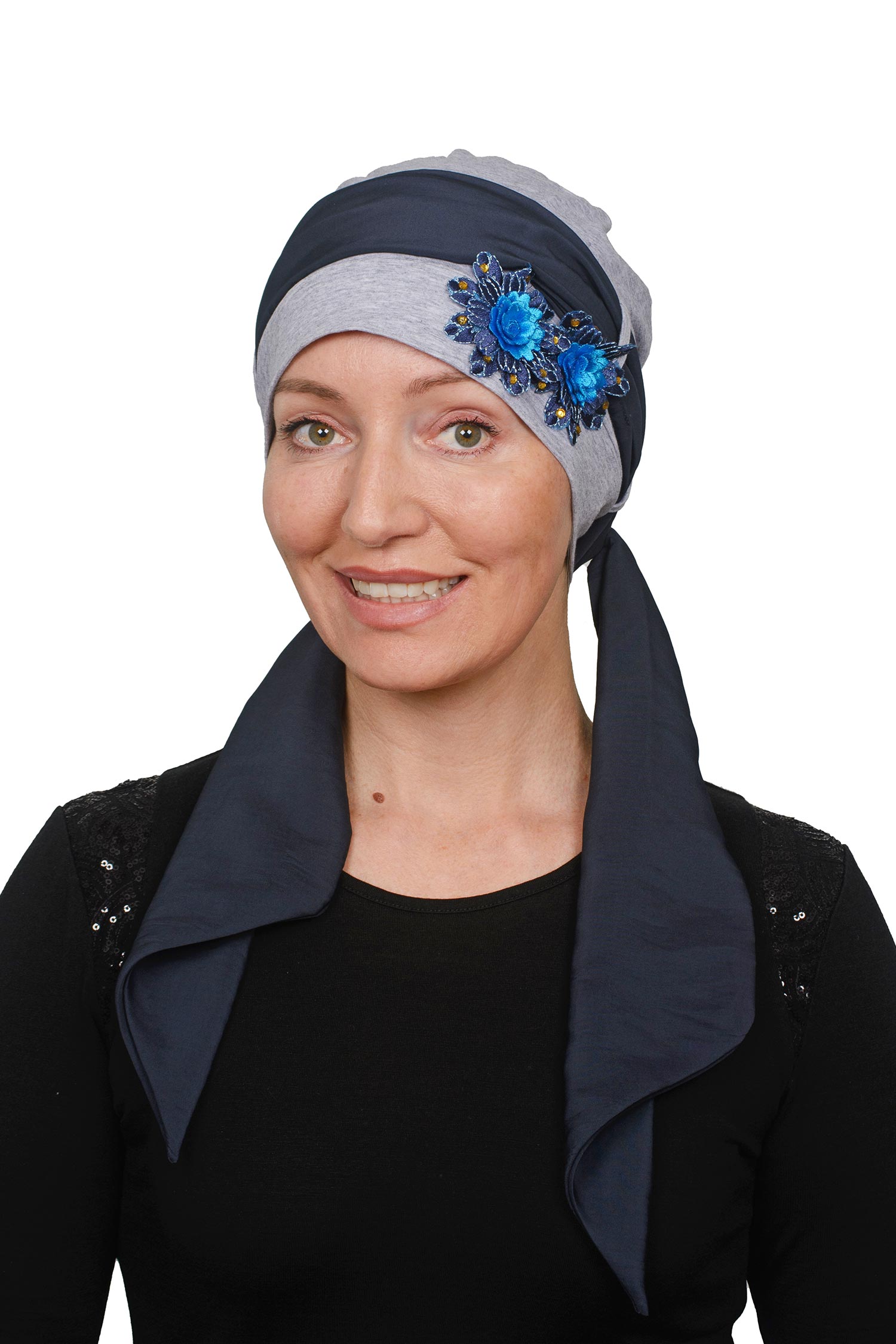 Woman wearing a gray cancer headscarf with blue floral embellishments on a white background