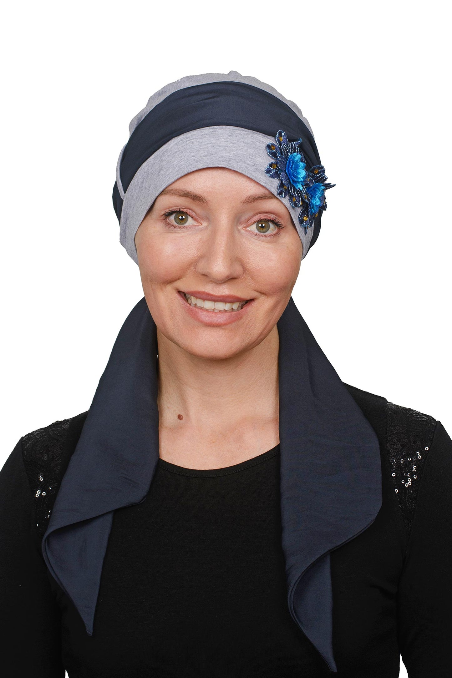 Woman wearing a cancer headscarf with a blue flower accessory on a white background