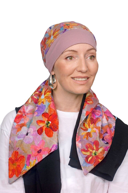 A women wearing a head scarf in pretty pink with a floral design on it as a head covering