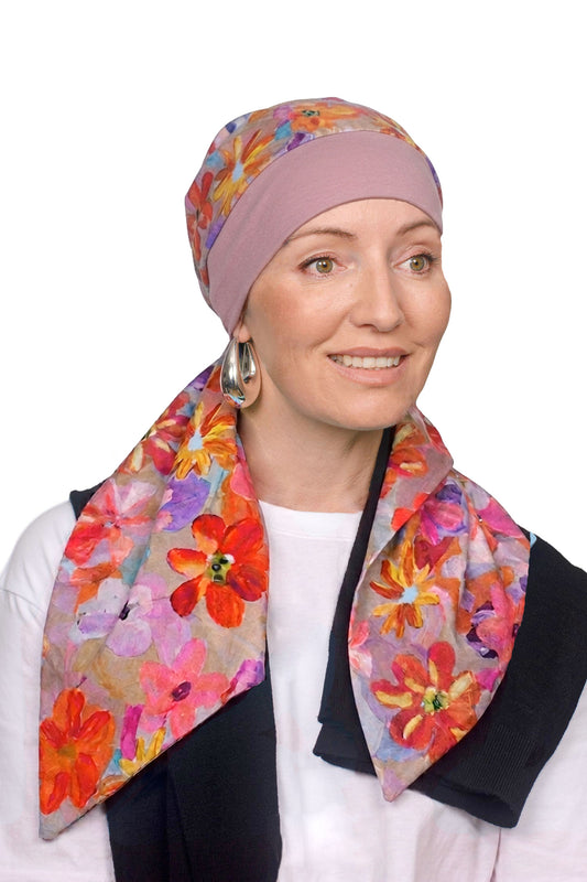 A women wearing a head scarf in pretty pink with a floral design on it as a head covering