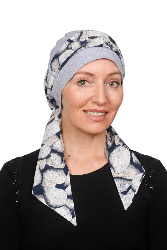 A women wearing a grey silver cancer cap with a scarf threaded through as a headwrap