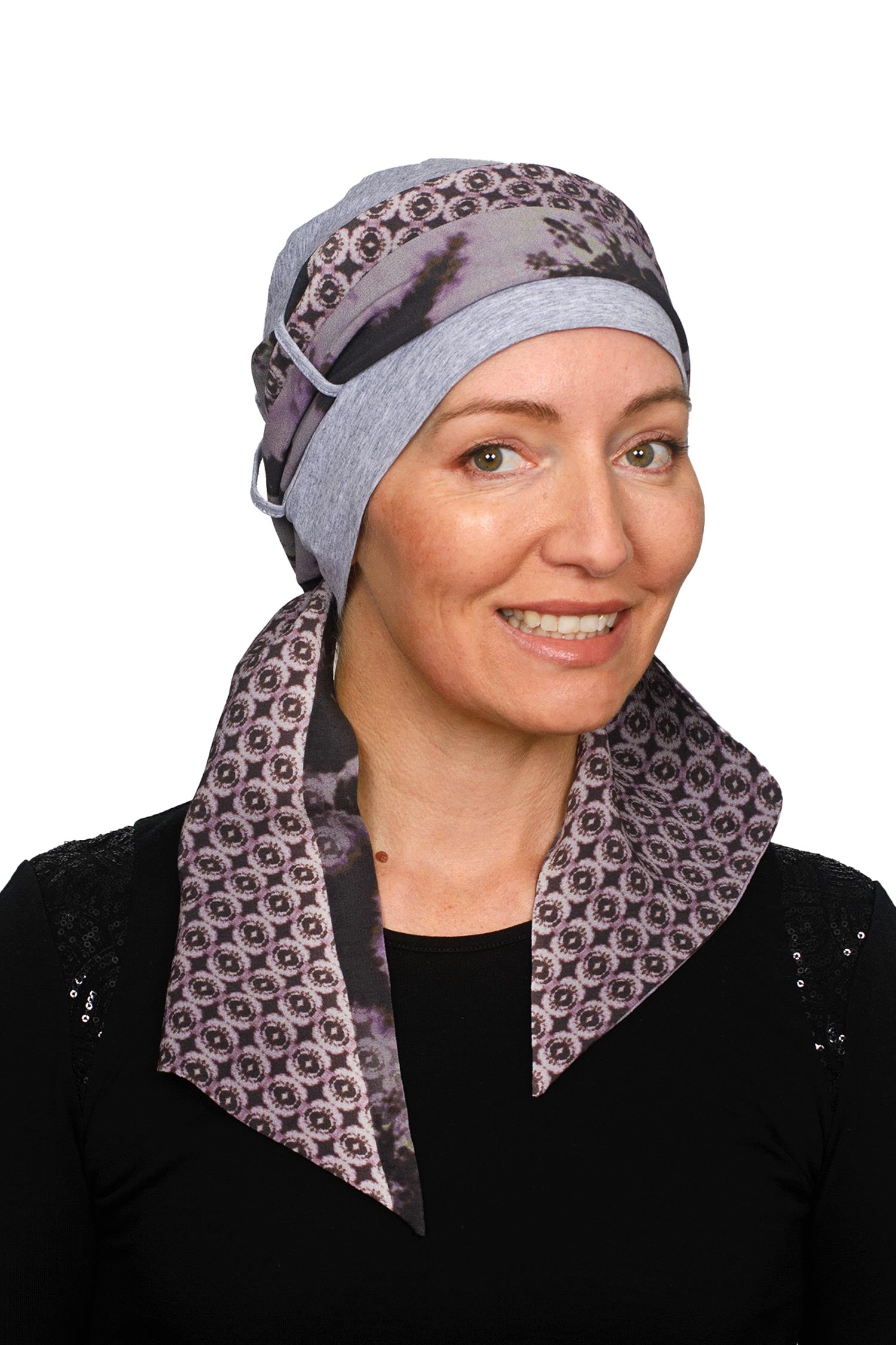 A women wearing a cancer cap with cancer headscarf in muted colours as a headcovering.