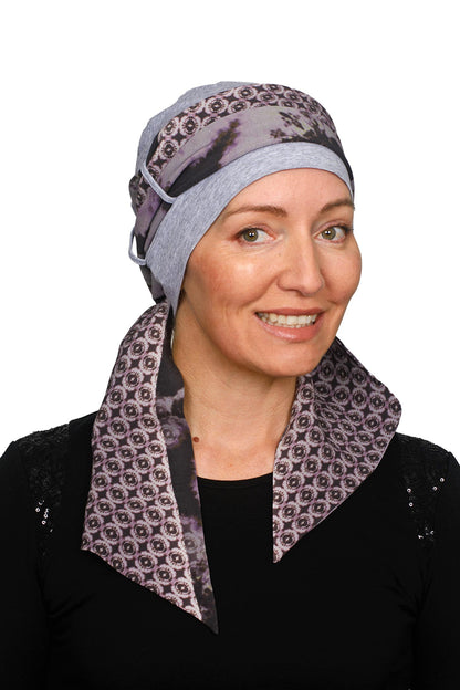 A women wearing a cancer cap with cancer headscarf in muted colours as a headcovering.