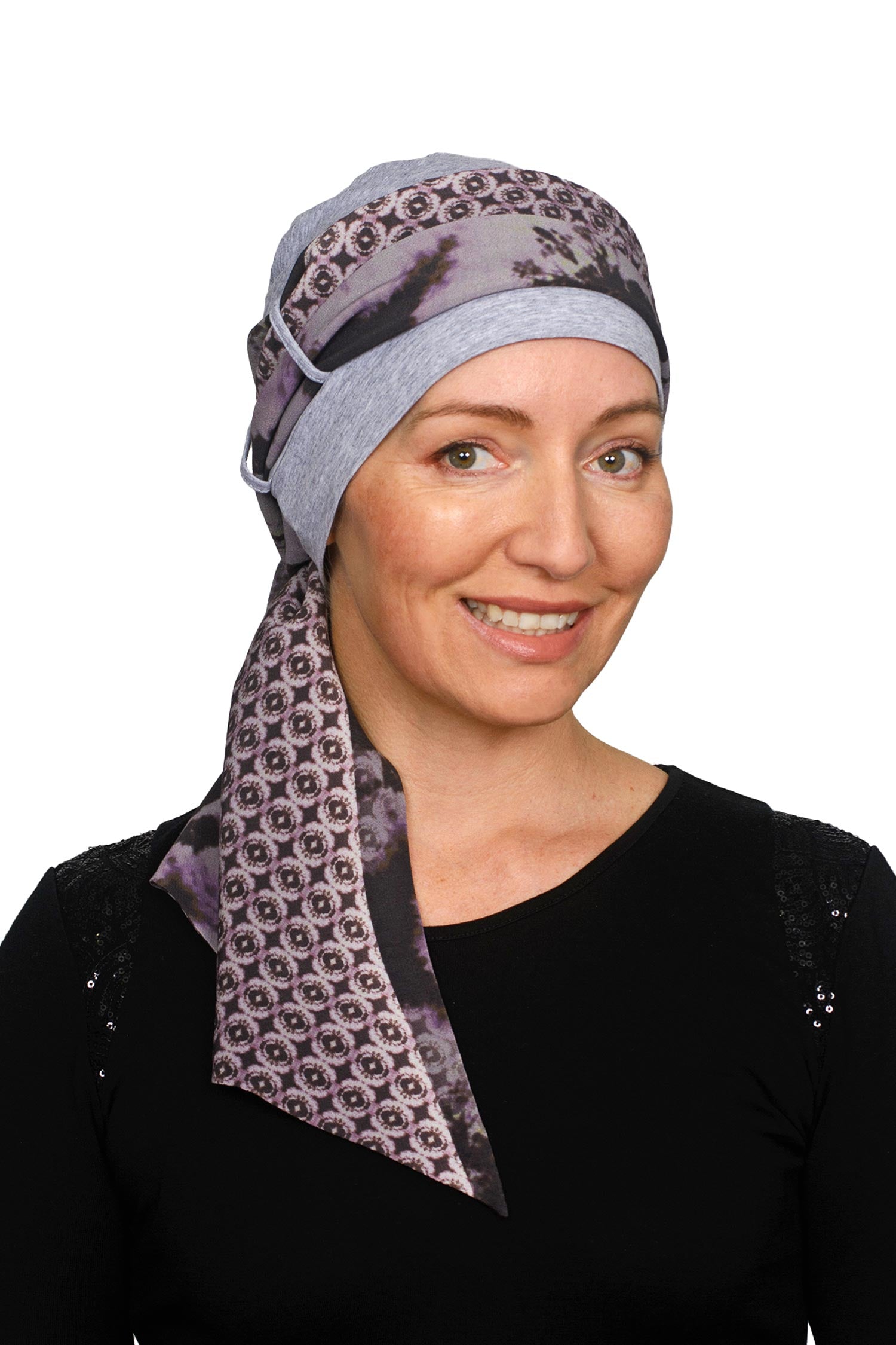A women wearing a cancer cap with cancer headscarf in muted colours as a headcovering.