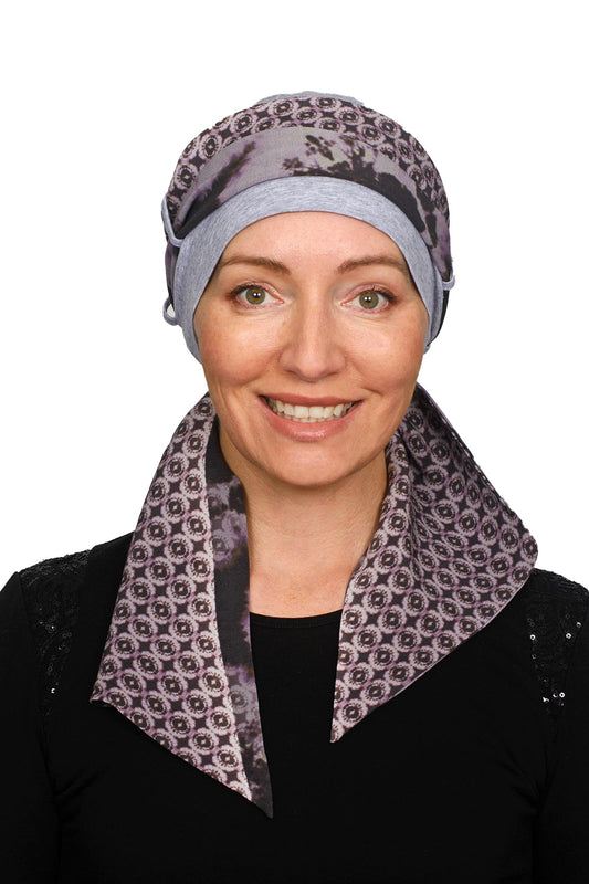 A women wearing a cancer cap with cancer headscarf in muted colours as a headcovering.