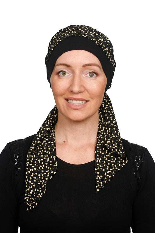 A women wearing a black cancer hat with a ditsy floral scarf as a headcovering