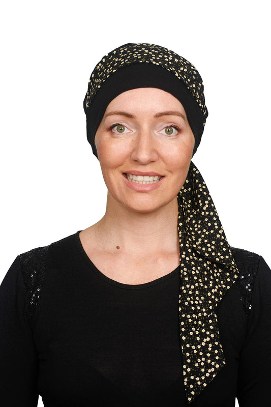 A women wearing a black cancer hat with a ditsy floral scarf as a headcovering