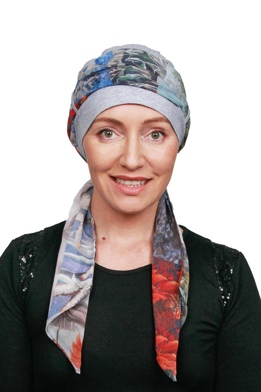 Women wearing a silver marle cap for cancer with a scarf in a floral print as a headwrap in nz