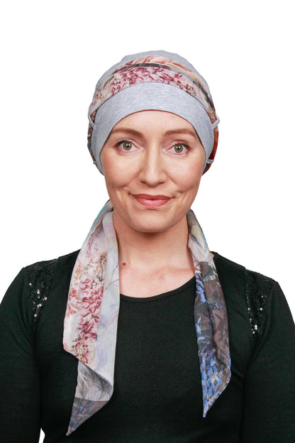 Women wearing a silver marle cap for cancer with a scarf in a floral print as a headwrap in nz