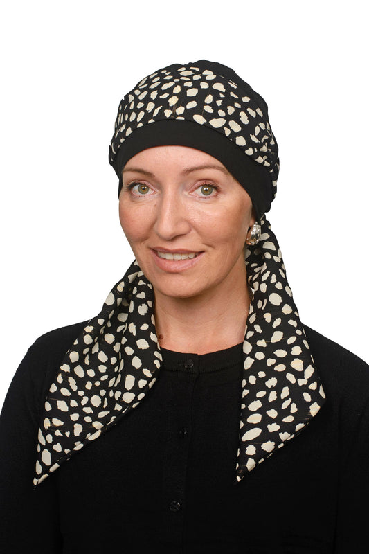 Women wearing a black cancer cap with an animal printed scarf with lurex through it as a head covering