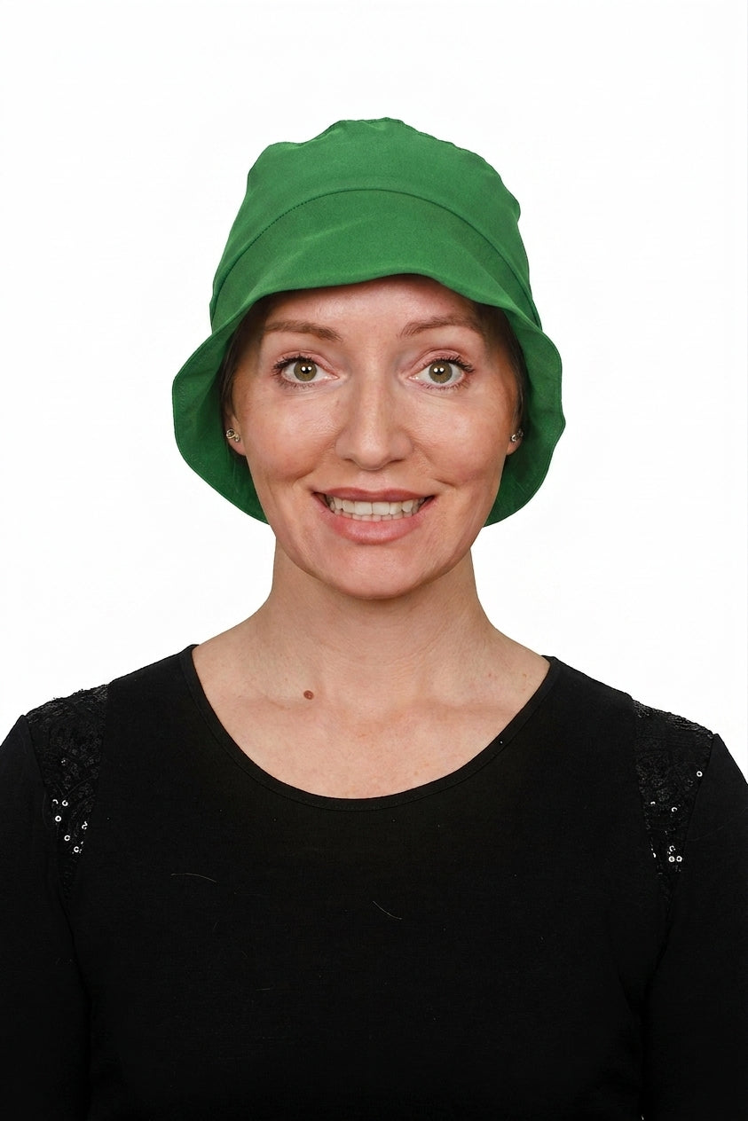 A woman wearing a cancer bright green cloche sun hat and a black top, photographed against a plain white background.