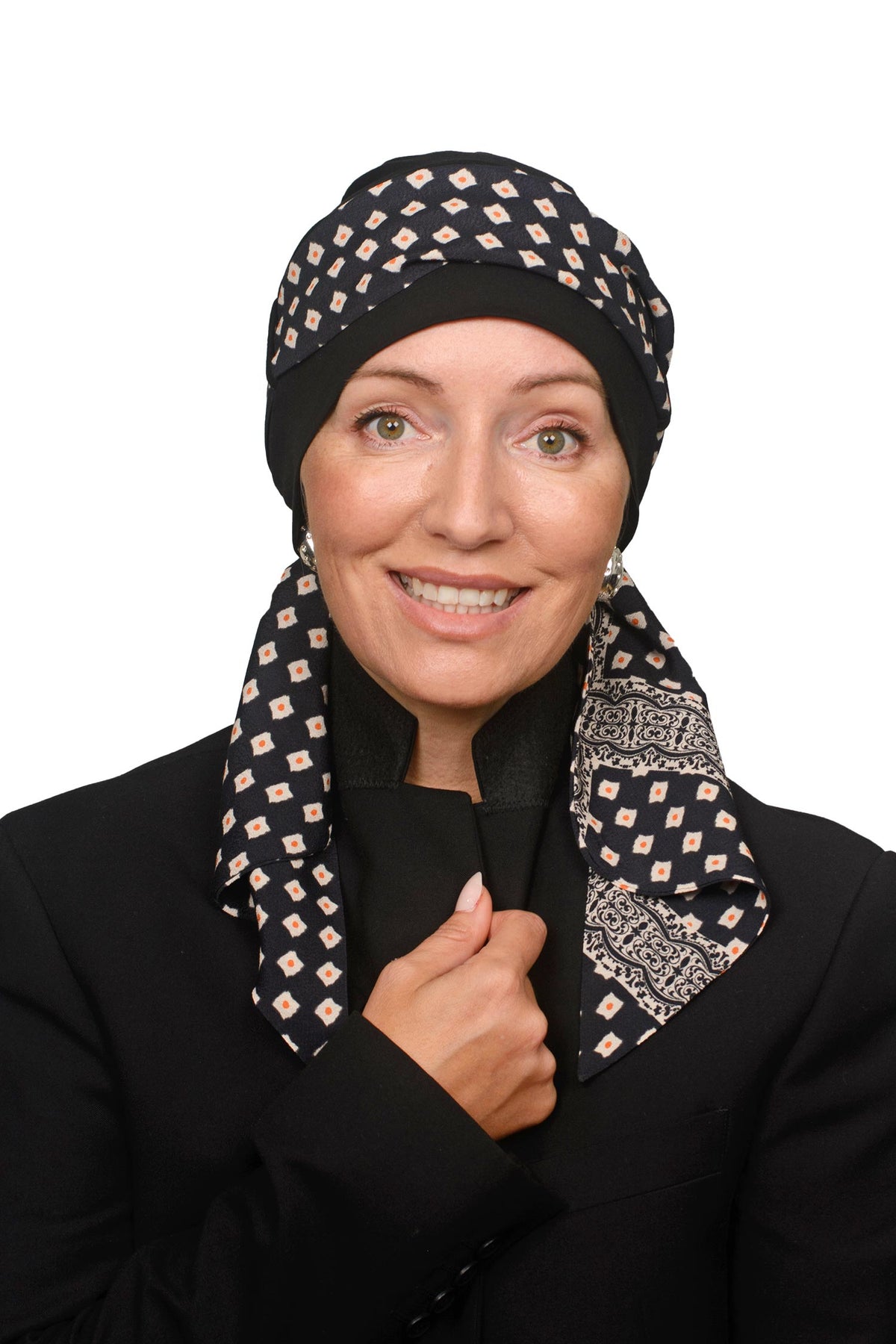 A woman wearing a black headscarf with a beige geometric diamond pattern and a matching patterned neck scarf, paired with a black jacket, against a plain white background.