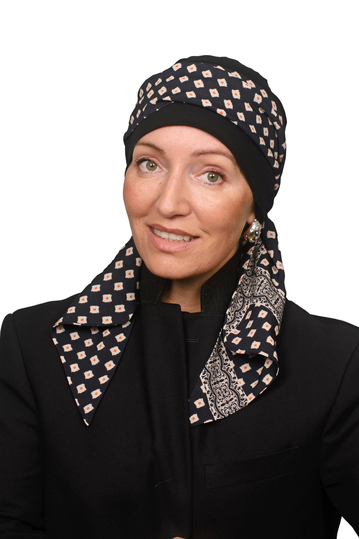 A woman wearing a black and beige patterned headscarf and matching neck scarf, paired with a black blazer, against a plain white background.