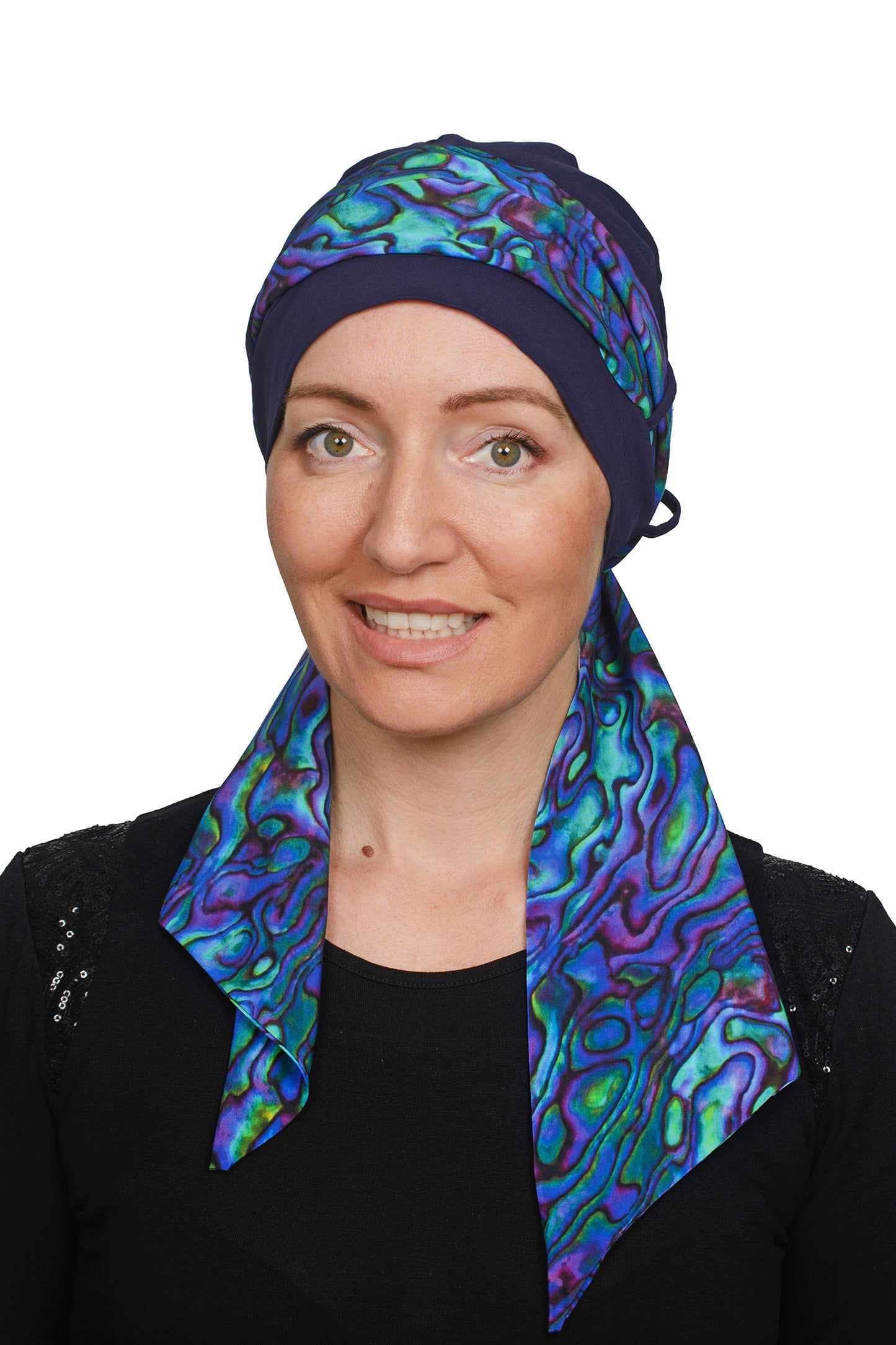 Women wearing a headcovering cancer scarf with cap in an ink and paua design
