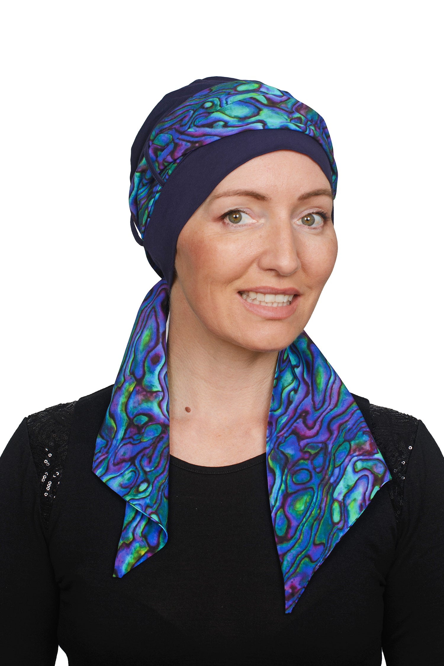 Women wearing a headcovering cancer scarf with cap in an ink and paua design