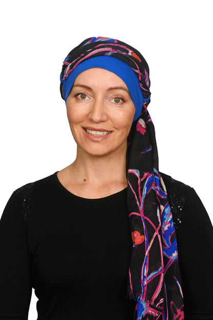 A women wearing a ocean blue cancer hat with a floral scarf as a headcovering