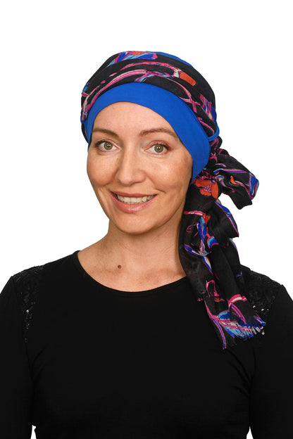 A women wearing a ocean blue cancer hat with a floral scarf as a headcovering