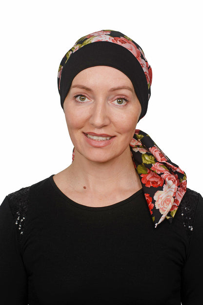 Women wearing a cancer hat in a rose print with a black band as a head covering with a scrunchie