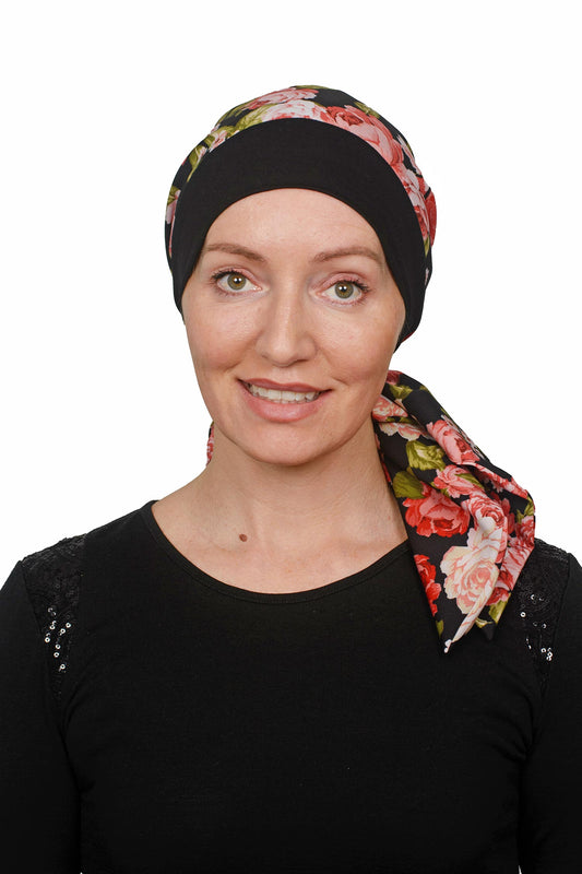 Women wearing a cancer hat in a rose print with a black band as a head covering with a scrunchie