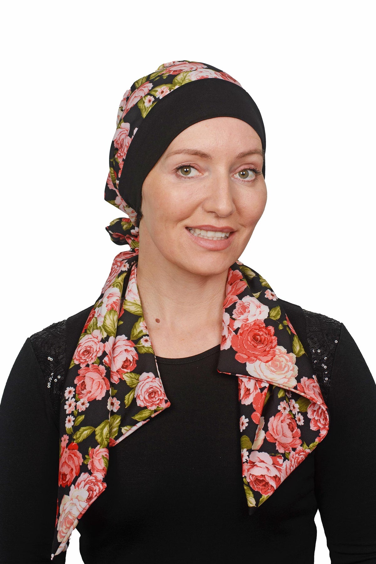Women wearing a cancer hat in a rose print with a black band as a head covering with a scrunchie