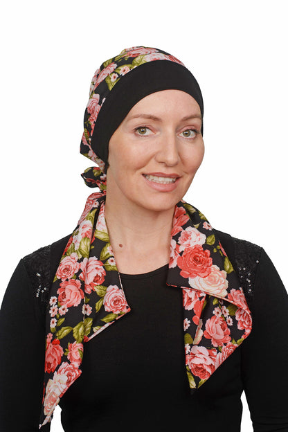 Women wearing a cancer hat in a rose print with a black band as a head covering with a scrunchie