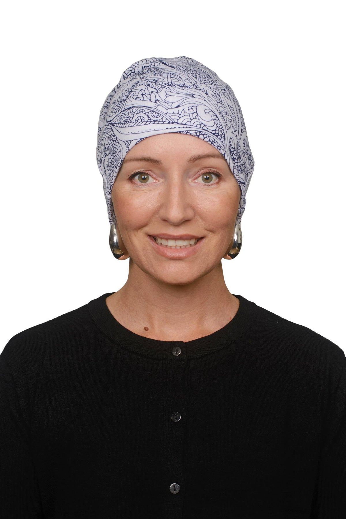 A woman wearing a light blue and white paisley patterned headscarf and a black top, photographed against a solid white background.