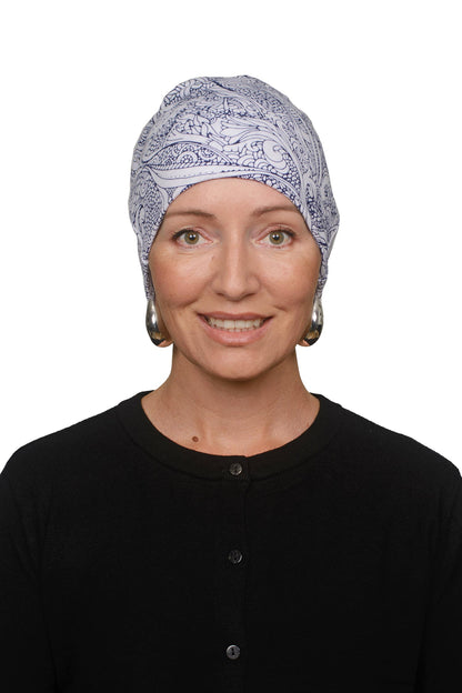 A woman wearing a light blue and white paisley patterned headscarf and a black top, photographed against a solid white background.