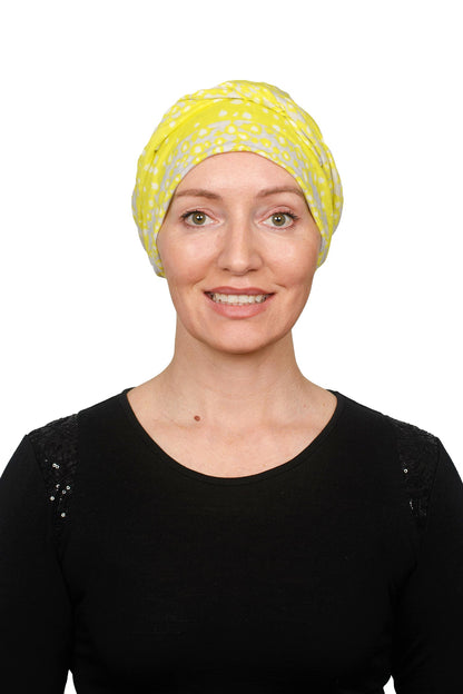 Women wearing a cancer scarf made out of linen in a yellow colour wrapped around her head as a headcovering