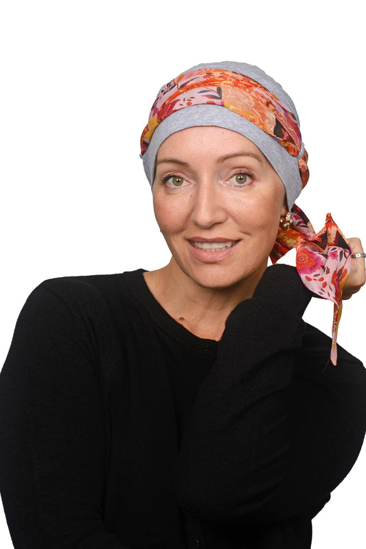 Women wearing a silver cap with a yellow pretty paisley print scarf as a headcovering for cancer