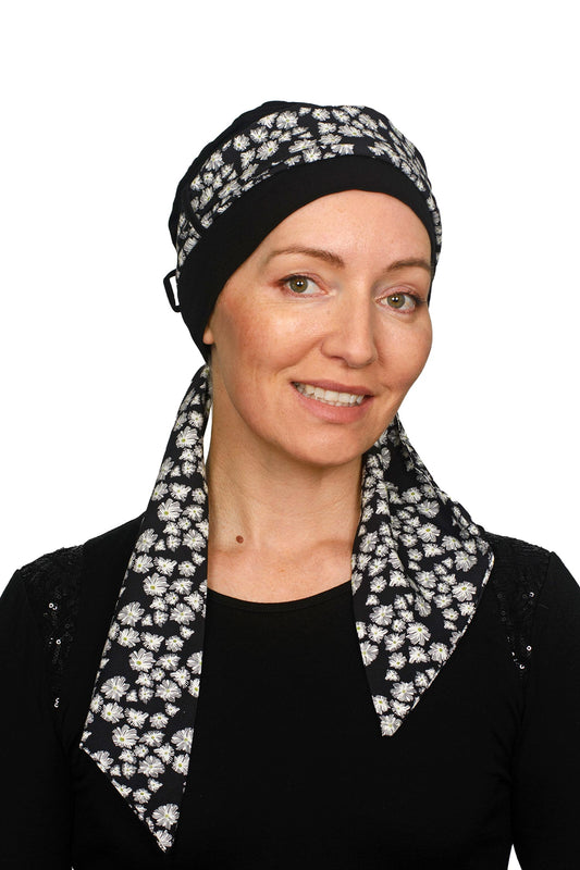 Women wearing a black cancer cap with a daisy print on it as a head covering